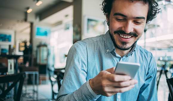 Uomo in un ufficio che guarda il suo cellulare e ride 