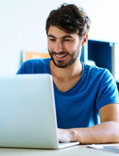 Uomo che sorride mentre lavora al suo portatile 