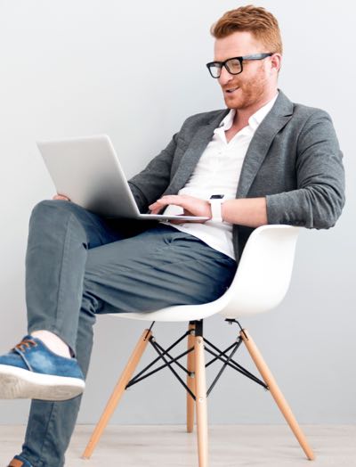 Man on a chair working with his laptop on lis lap